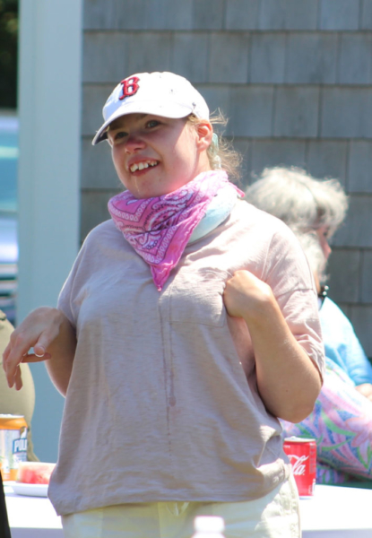 Woman with ball cap smiling, outside during a cookout