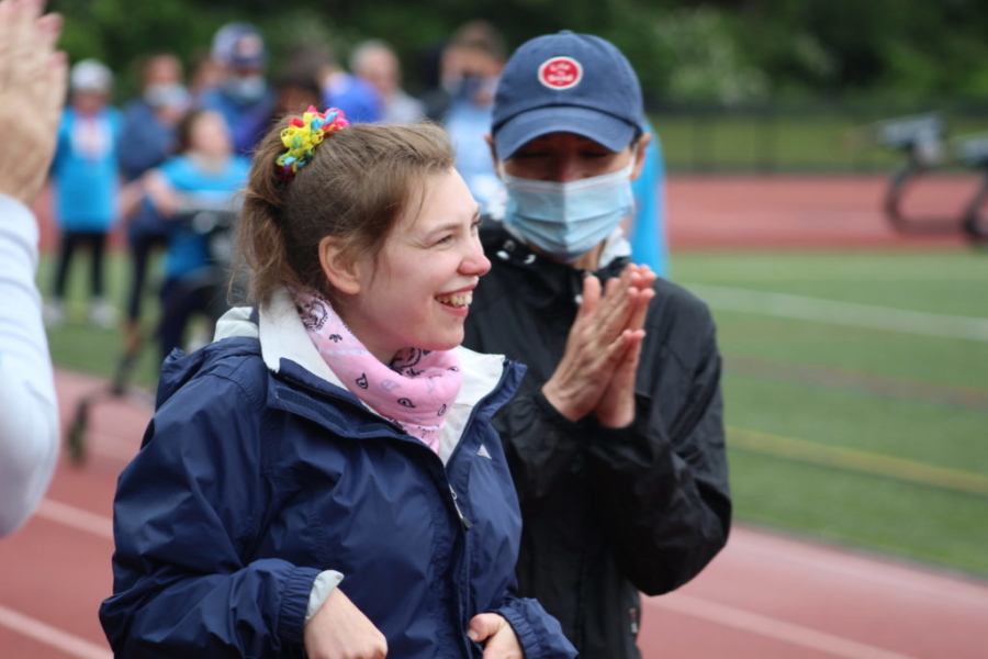 Smiling woman on the track field, with clapping caregiver