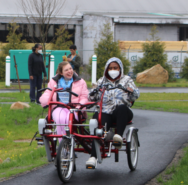 CCV resident and caregiver riding an adult three wheeld bike on the bike trail in Orleans